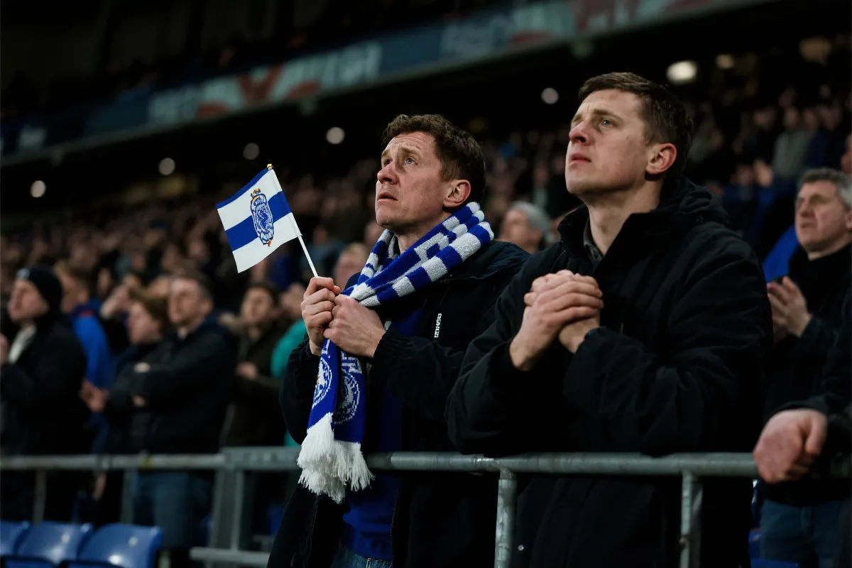 世界杯淘汰赛点球大战前的看台：球迷紧握围巾与旗帜，灯光聚焦，紧张氛围